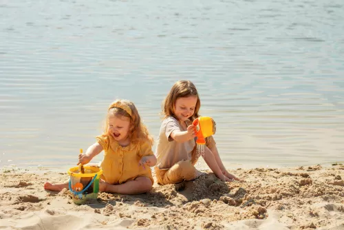 Kinder spielen am Strand mit recycelten Spielzeugen